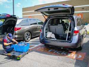 Minivan getting curbside groceries delivered and loaded into their trunk