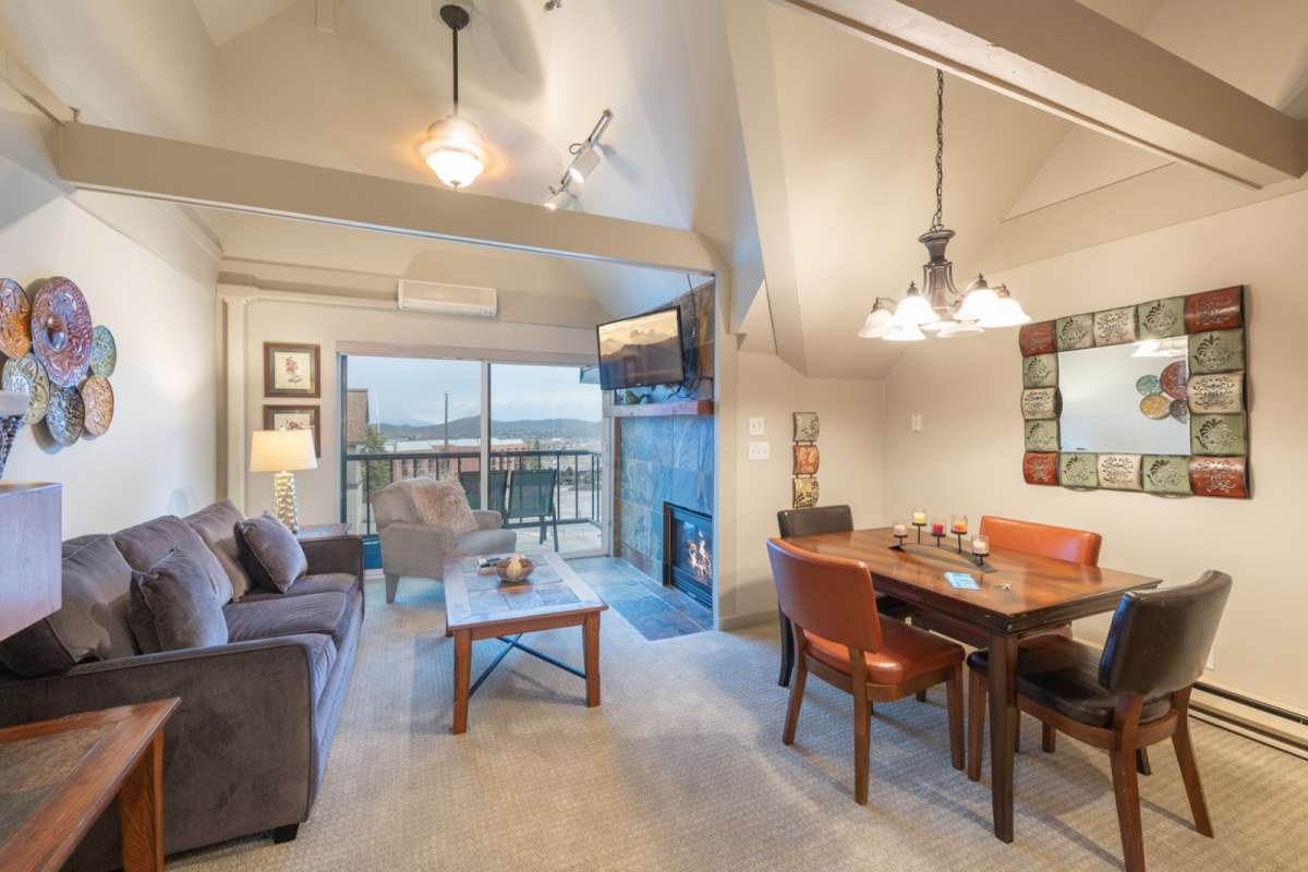 Living room with a grey couch on the left and a fireplace on the right, the view from the window shows The best-located home in Park City.